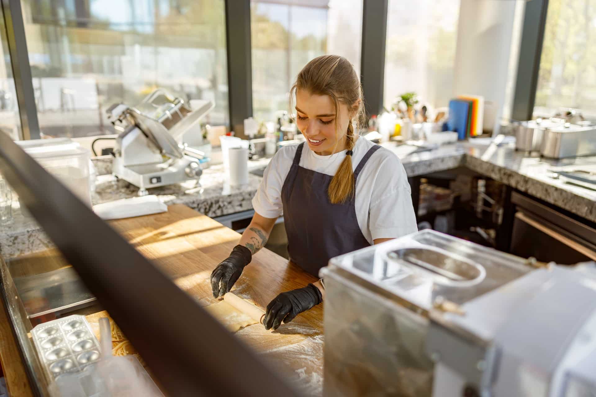 Junge Frau bereitet Teig in einer modernen Gastronomie-Küche zu | Salattheke